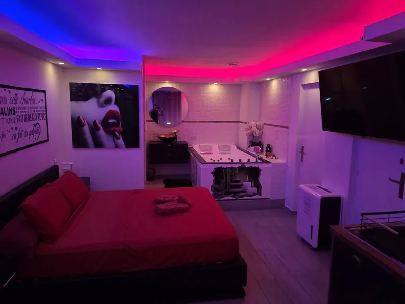 Vue d'ensemble de la suite avec éclairage d'ambiance rose et violet, baignoire balnéothérapie